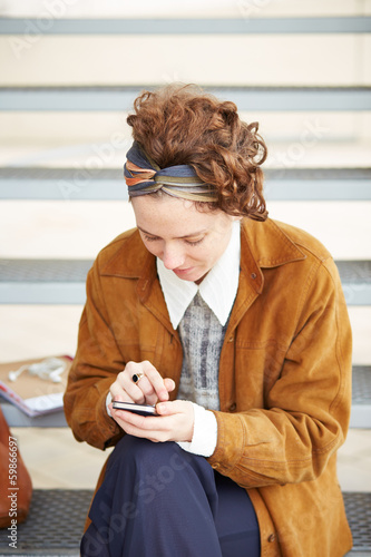 Photo: Young redhead hipster woman using smartphone Young redhead hipster woman using smartphone