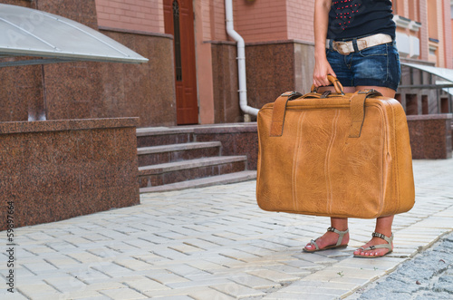 Photo: Woman waiting with her suitcase in the street Woman waiting with her suitcase in the street