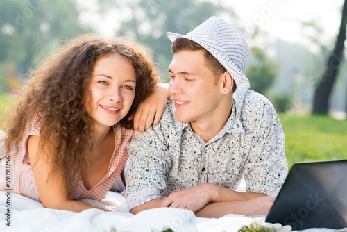 Photo: couple lying together in a park with laptop couple lying together in a park with laptop