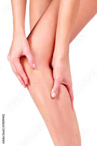 Photo: Woman holding sore knee, on white background Woman holding sore knee, on white background