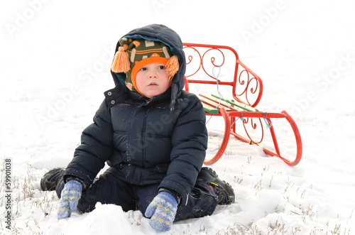 Photo: Small boy kneeling in the snow with a sled Small boy kneeling in the snow with a sled