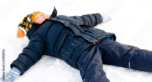 Photo: Happy little boy making snow angels in the snow Happy little boy making snow angels in the snow