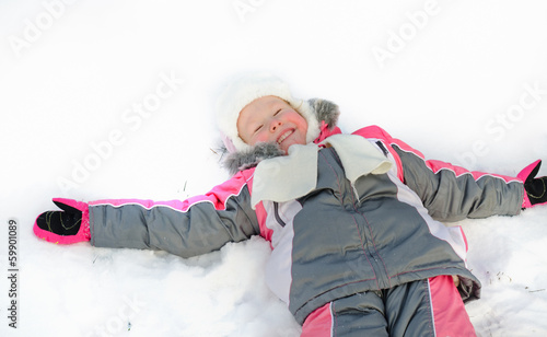 Photo: Laughing little girl lying in the snow Laughing little girl lying in the snow