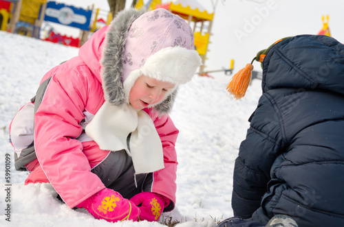 Photo: Cute little girl gathering snowballs in the snow Cute little girl gathering snowballs in the snow