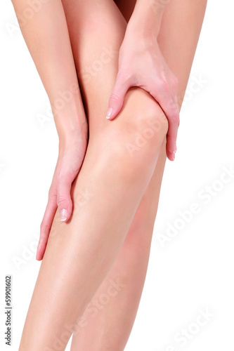 Photo: Woman holding sore knee, isolated on white background Woman holding sore knee, isolated on white background