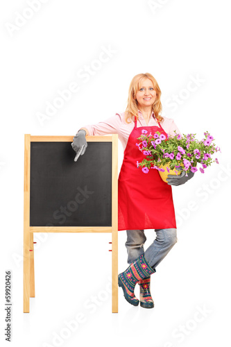 Photo: Female gardener standing next to black table and holding flowers Female gardener standing next to black table and holding flowers
