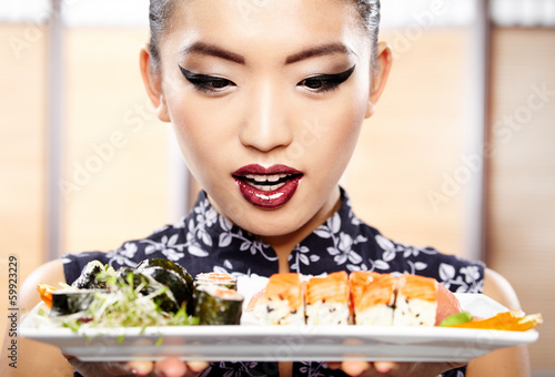 Photo: Beautiful young woman eating sushi. Shallow depth of field, focu Beautiful young woman eating sushi. Shallow depth of field, focu