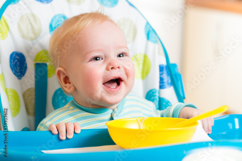 Photo: smiling baby eating food on kitchen smiling baby eating food on kitchen