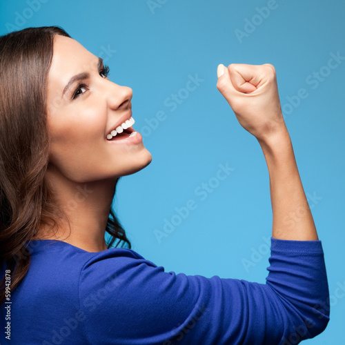 Photo: Happy gesturing young woman, over blue Happy gesturing young woman, over blue