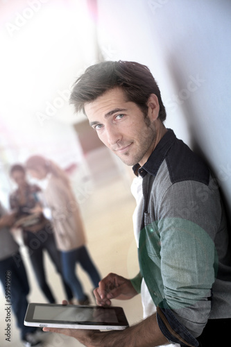 Photo: Young man in college campus connected on tablet Young man in college campus connected on tablet