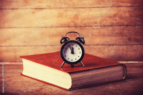 Photo: Alarm clock and book. Alarm clock and book.