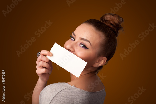Photo: Cute girl holding white card at front of her lips with copy spac Cute girl holding white card at front of her lips with copy spac