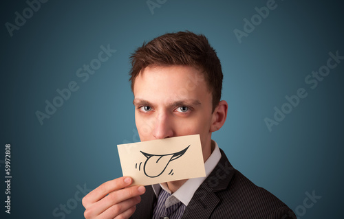 Photo: Happy businessman holding funny white card on his mouth Happy businessman holding funny white card on his mouth