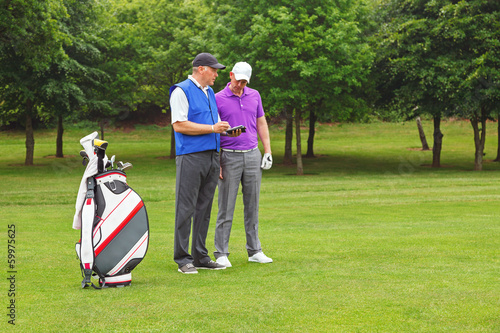 Photo: Golfer and caddy looking at a course guide Golfer and caddy looking at a course guide