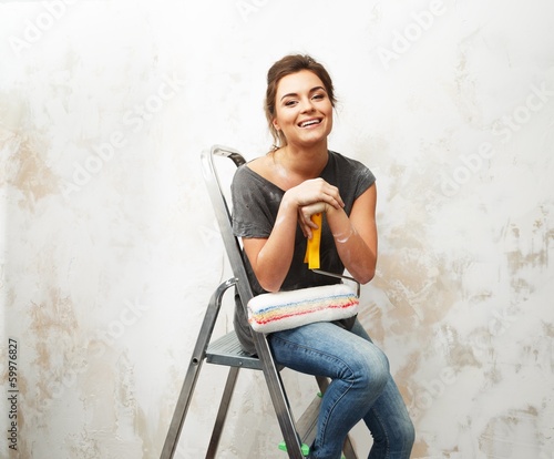 Photo: Happy beautiful young woman doing wall painting Happy beautiful young woman doing wall painting