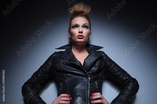 Photo: woman in leather jacket standing with hands on hips and looking woman in leather jacket standing with hands on hips and looking
