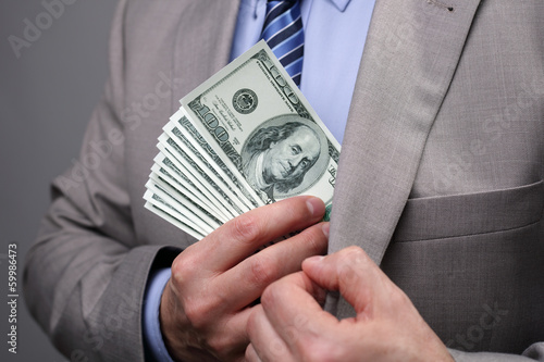 Photo: Businessman putting money in pocket Businessman putting money in pocket