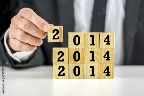Photo: Businessman with 2014 New Year building blocks Businessman with 2014 New Year building blocks