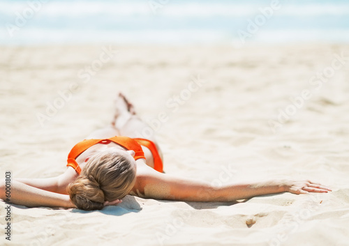 Photo: Young woman laying on beach. rear view Young woman laying on beach. rear view