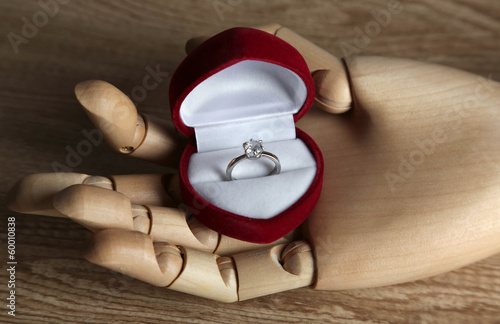 Photo: Box with ring in wooden hand isolated on white Box with ring in wooden hand isolated on white