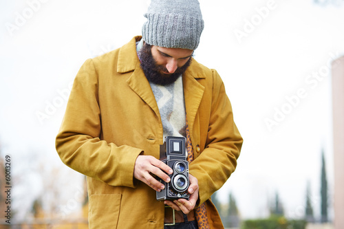 Photo: Young bearded hipster taking photo with TLR camera Young bearded hipster taking photo with TLR camera