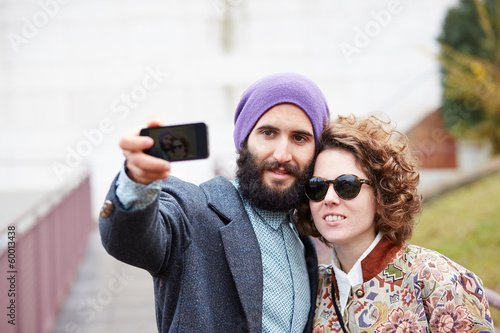 Photo: Couple taking a photograph of themselves with a smartphone Couple taking a photograph of themselves with a smartphone