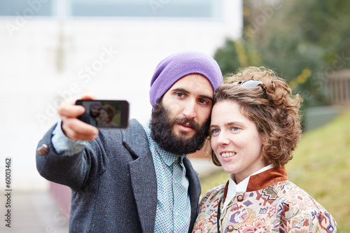 Photo: Couple taking a photograph of themselves with a smartphone Couple taking a photograph of themselves with a smartphone