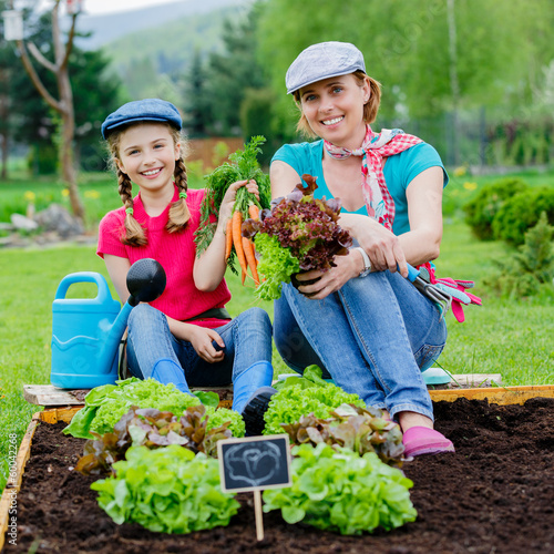 Photo: Gardening - girl with mother working in the garden Gardening - girl with mother working in the garden