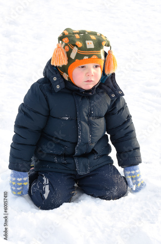 Photo: Cute small boy kneeling in winter snow Cute small boy kneeling in winter snow