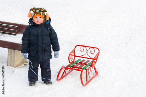 Photo: Little boy in the snow with his toboggan Little boy in the snow with his toboggan