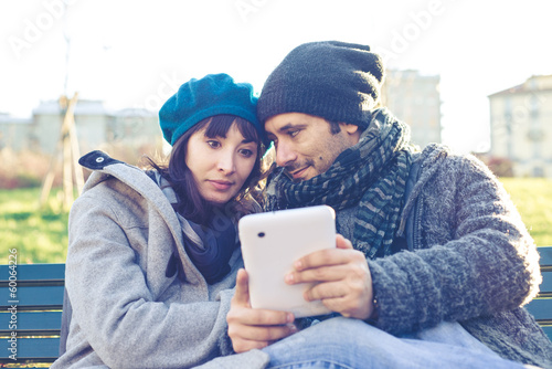 Photo: couple in love using tablet at the park couple in love using tablet at the park