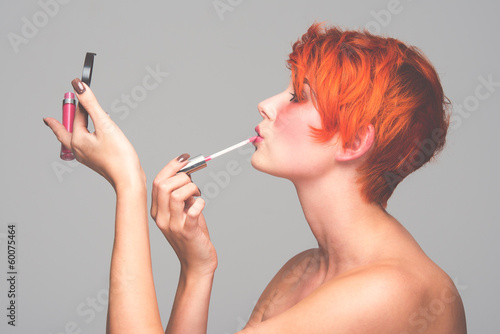 Photo: a young red-haired girl putting on makeup a young red-haired girl putting on makeup