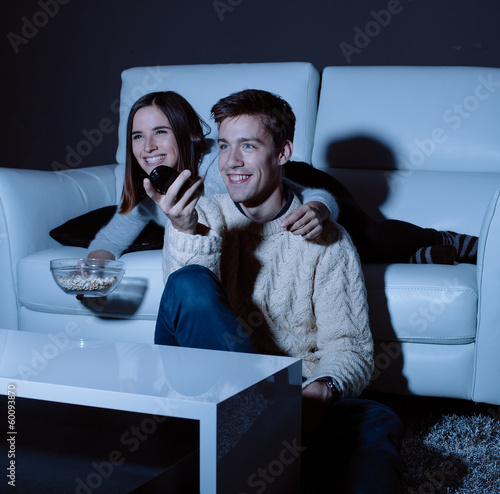 Photo: Young couple in love watching TV at night Young couple in love watching TV at night