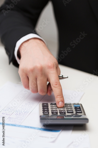 Photo: close up of businessman with papers and calculator close up of businessman with papers and calculator