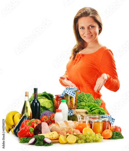 Photo: Young woman with variety of grocery products isolated on white Young woman with variety of grocery products isolated on white