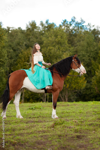 Photo: Beautiful woman with a horse in the field. Girl on a farm with a Beautiful woman with a horse in the field. Girl on a farm with a