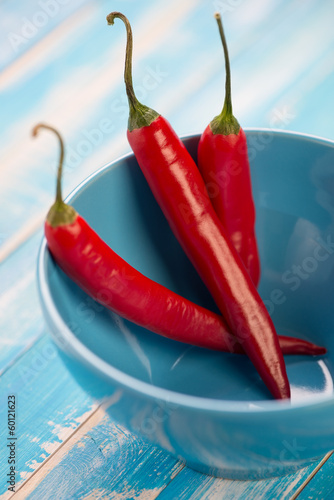 Photo: Red chili peppers in a turquoise glass bowl, close-up Red chili peppers in a turquoise glass bowl, close-up