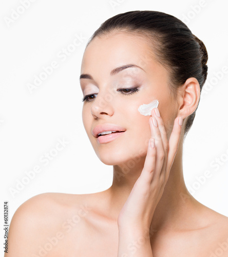 Photo: Beautiful woman applying cream on face Beautiful woman applying cream on face