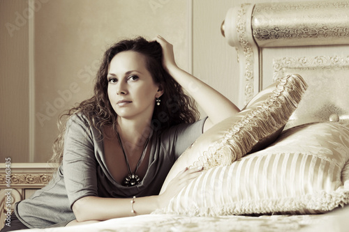 Photo: Beautiful woman relaxing in a bedroom Beautiful woman relaxing in a bedroom