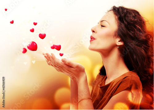 Photo: Woman Blowing Hearts from her Hands. St. Valentines Day Concept Woman Blowing Hearts from her Hands. St. Valentines Day Concept