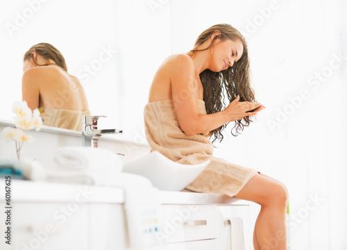 Photo: Young woman sitting with wet hair in bathroom Young woman sitting with wet hair in bathroom