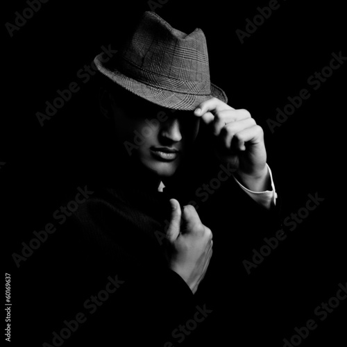 Photo: low key portrait of young gangster with hat in the darkness. low key portrait of young gangster with hat in the darkness.