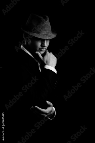 Photo: low key portrait of young gangster with hat in the darkness. low key portrait of young gangster with hat in the darkness.