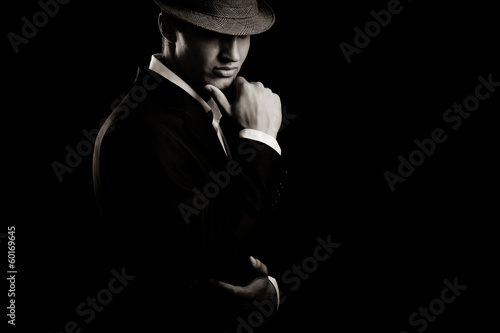 Photo: low key portrait of young gangster with hat in the darkness. low key portrait of young gangster with hat in the darkness.