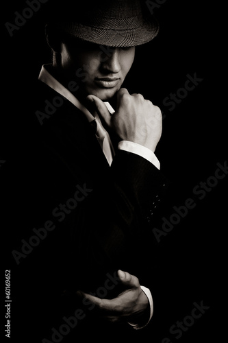 Photo: low key portrait of young gangster with hat in the darkness. low key portrait of young gangster with hat in the darkness.