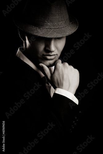 Photo: low key portrait of young gangster with hat in the darkness. low key portrait of young gangster with hat in the darkness.