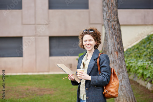 Photo: Female redhead student carrying notebook and coffee to go Female redhead student carrying notebook and coffee to go