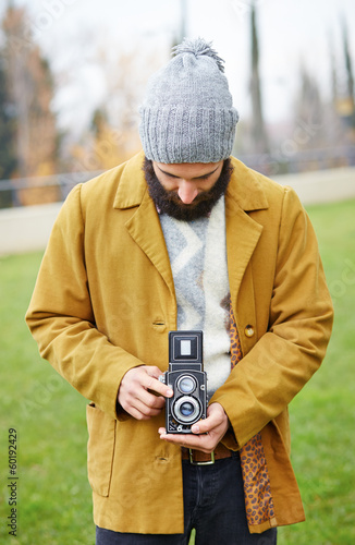 Photo: Young bearded hipster taking photo with TLR camera Young bearded hipster taking photo with TLR camera