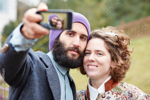 Photo: Couple taking a photograph of themselves with a smartphone Couple taking a photograph of themselves with a smartphone
