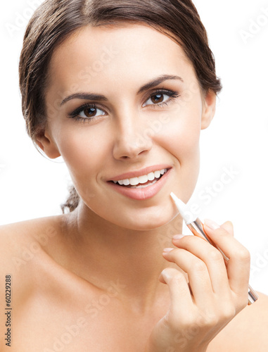 Photo: Smiling woman applying concealer on face, isolated Smiling woman applying concealer on face, isolated